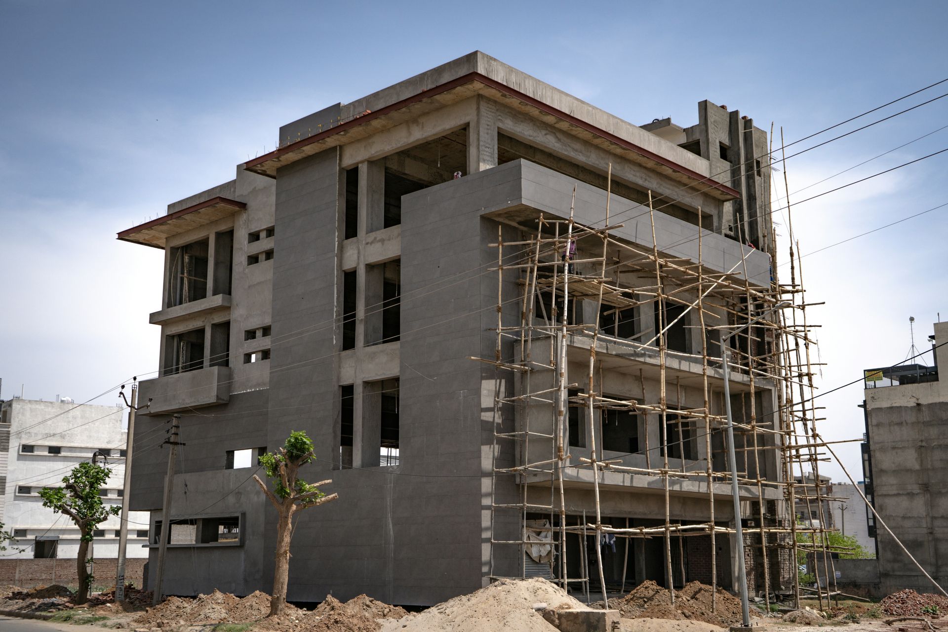 A multi-story concrete building under construction with bamboo scaffolding on the exterior